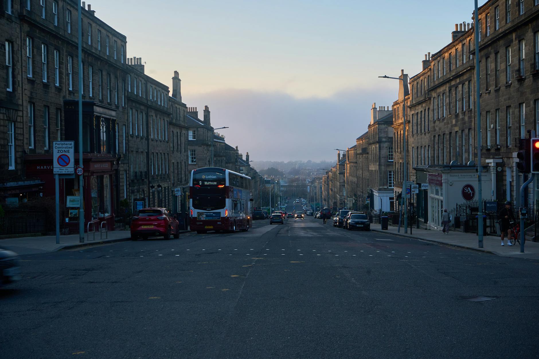 Red Lothian bus on an Edinburgh city street serving one of over 50 routes across the capital