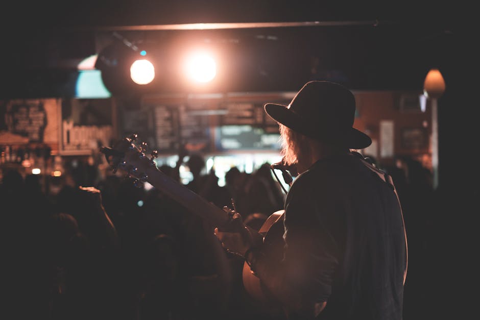 A guitarist in a hat performing under stage lights