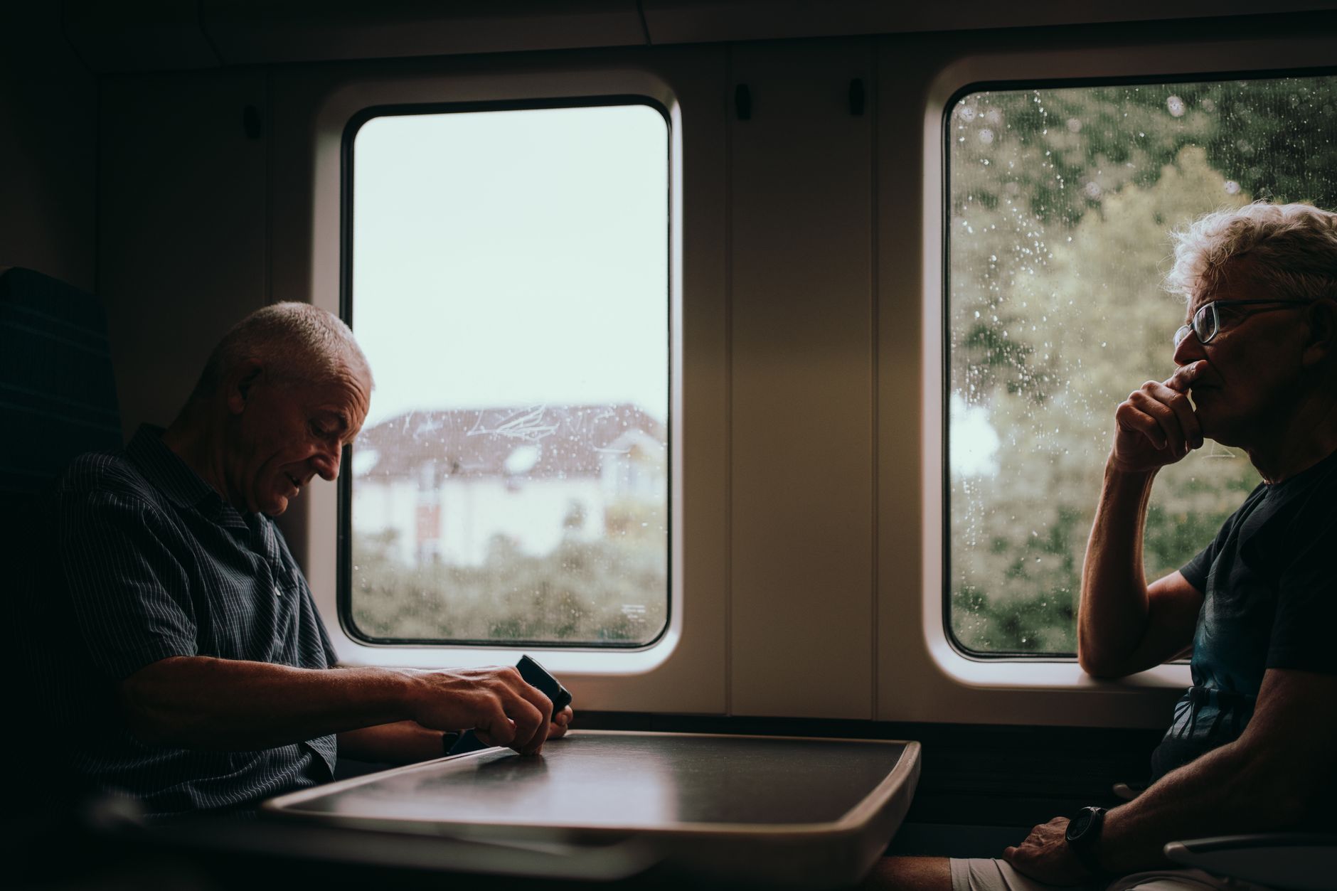 Passengers at a table seat on a British intercity train with countryside passing the window