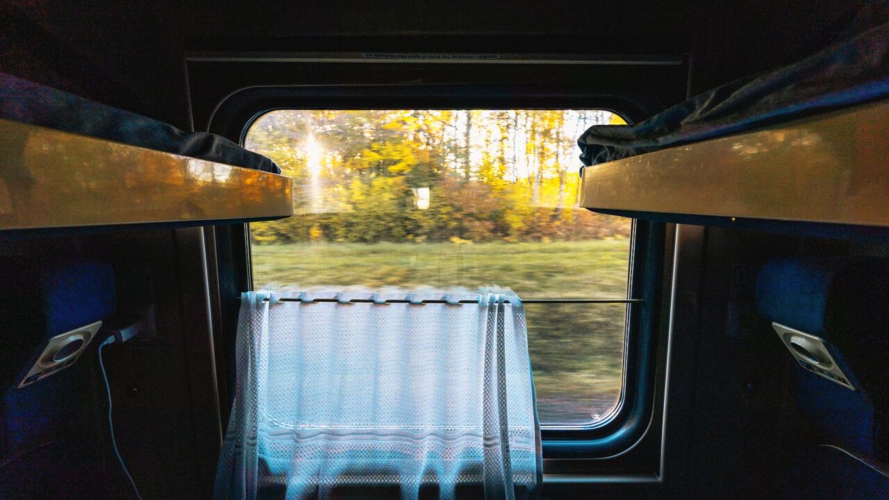 Looking out of a dimly lit train compartment window at first light