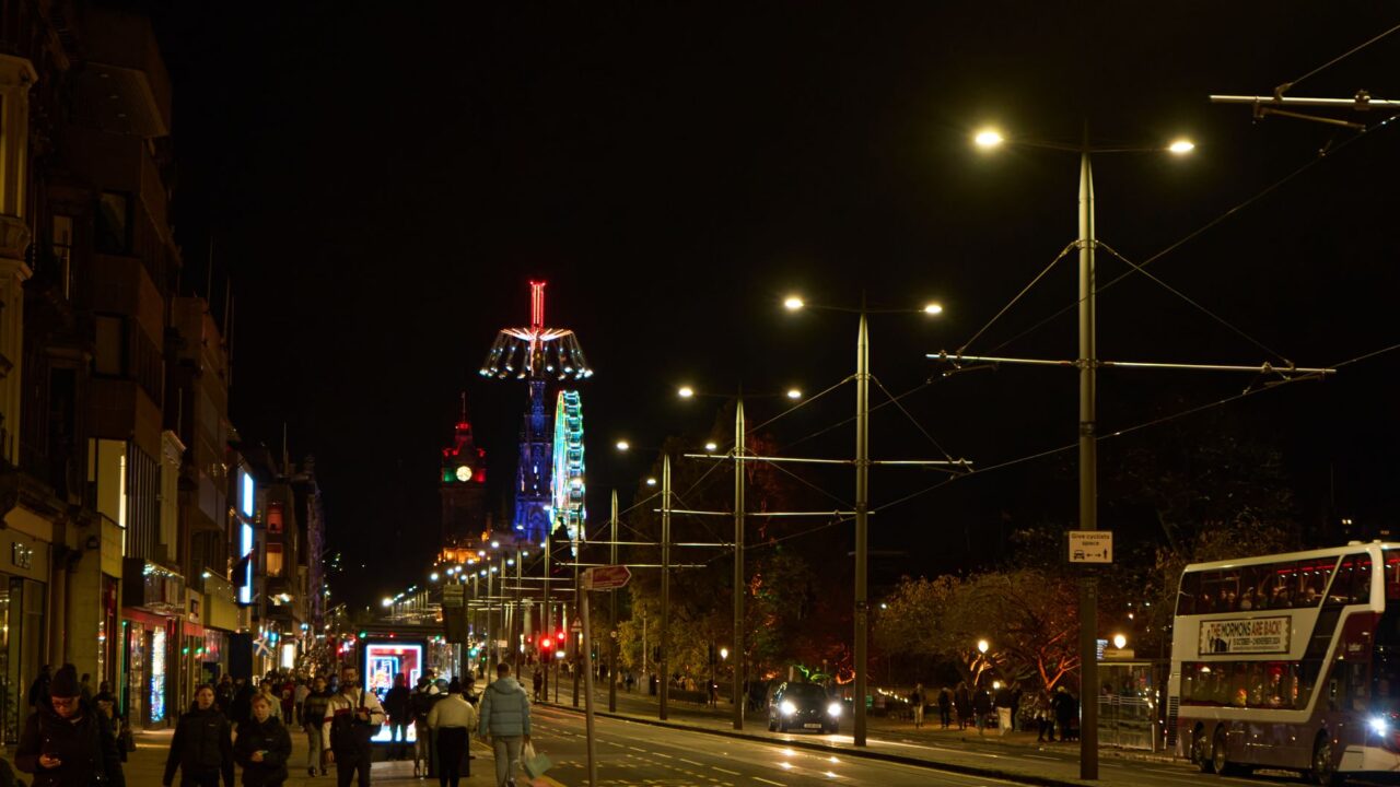 Princes Street Edinburgh at night with illuminated buildings and the Balmoral clock tower