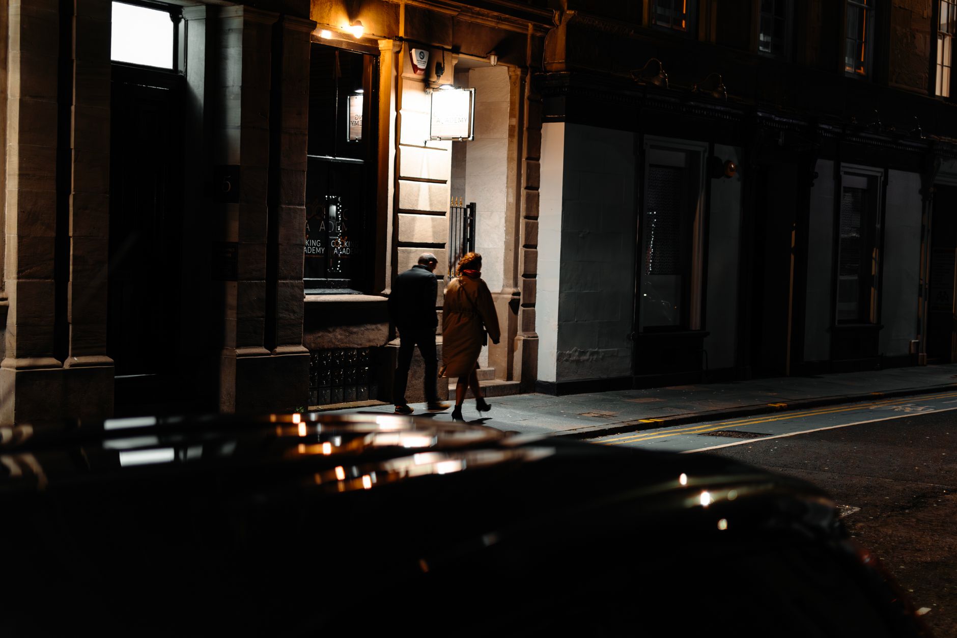 Two people walking along an Edinburgh street late at night