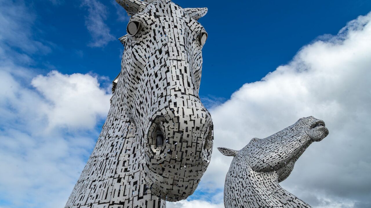 Close-up of the two Kelpies horse-head sculptures in Falkirk against a blue sky