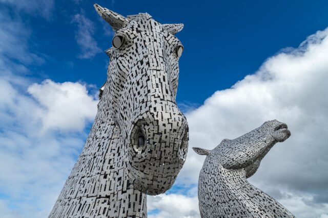 Close-up of the two Kelpies horse-head sculptures in Falkirk against a blue sky