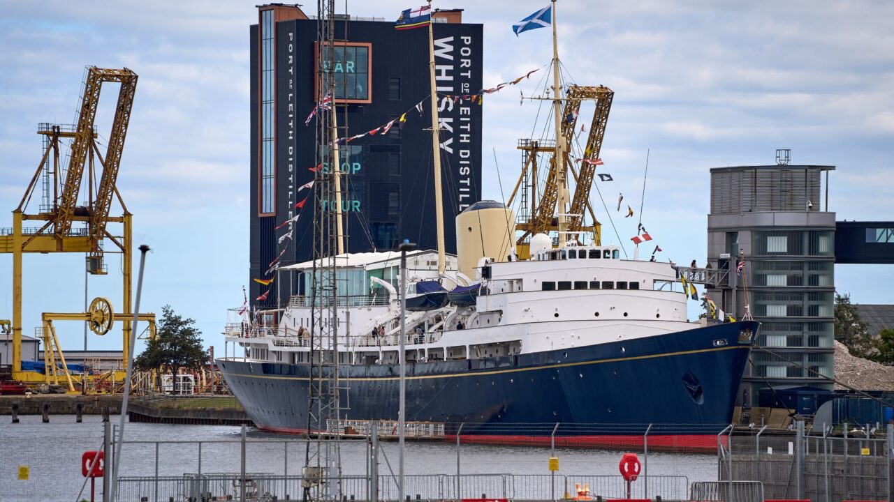 The Royal Yacht Britannia moored at Leith with dockyard cranes and the Port of Leith Distillery behind