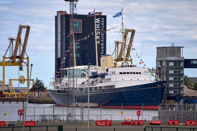 The Royal Yacht Britannia moored at Leith with dockyard cranes and the Port of Leith Distillery behind