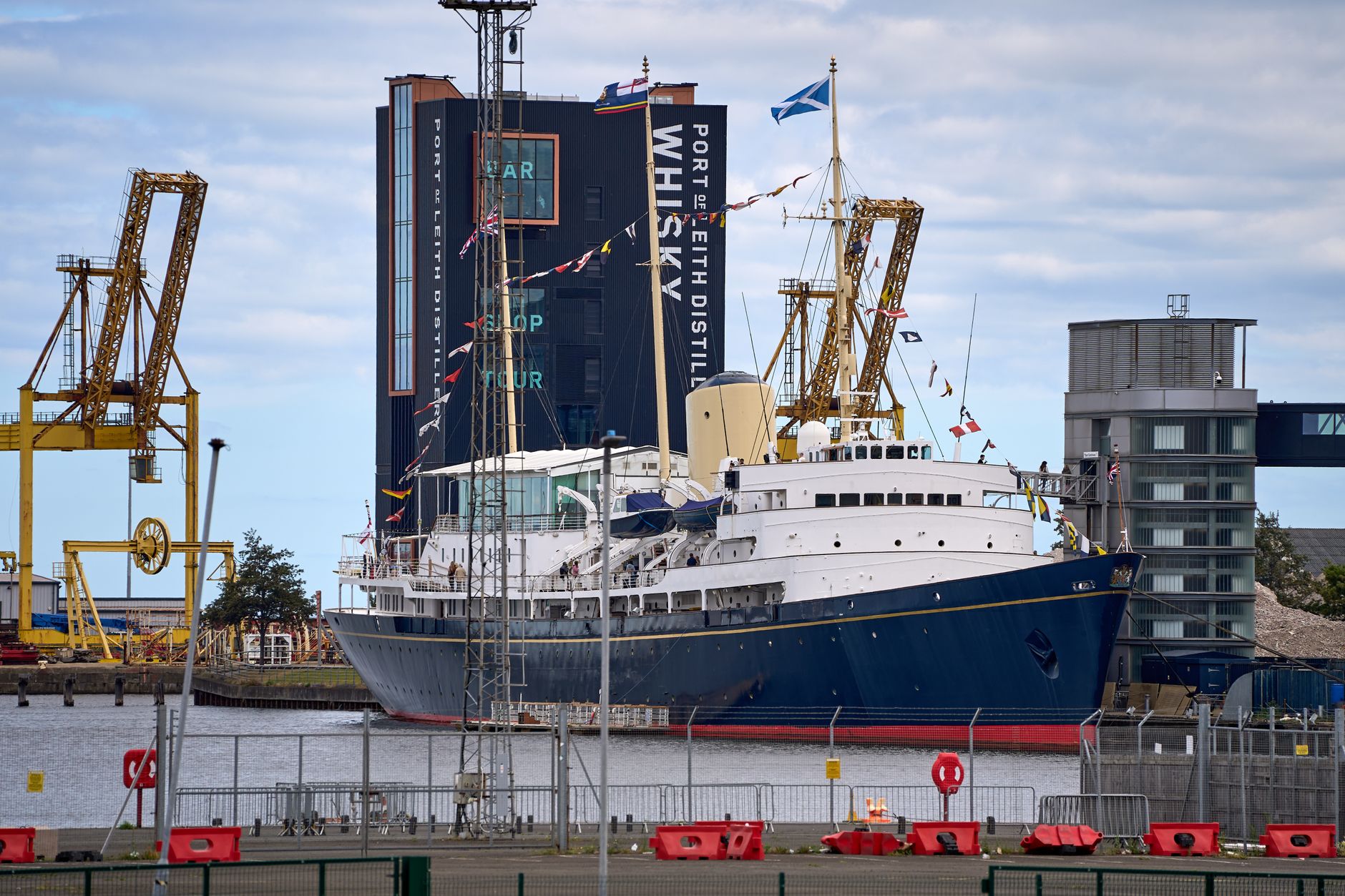 The Royal Yacht Britannia moored at Leith with dockyard cranes and the Port of Leith Distillery behind