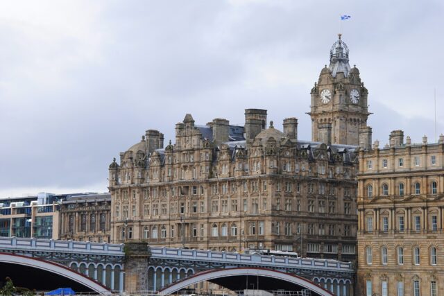 The Balmoral Hotel and its tall clock tower rise behind the iron arches of North Bridge in central Edinburgh.
