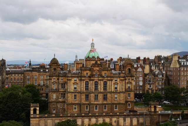 The Bank of Scotland headquarters in Edinburgh rises above trees, with a green central dome and ornate sandstone facade.