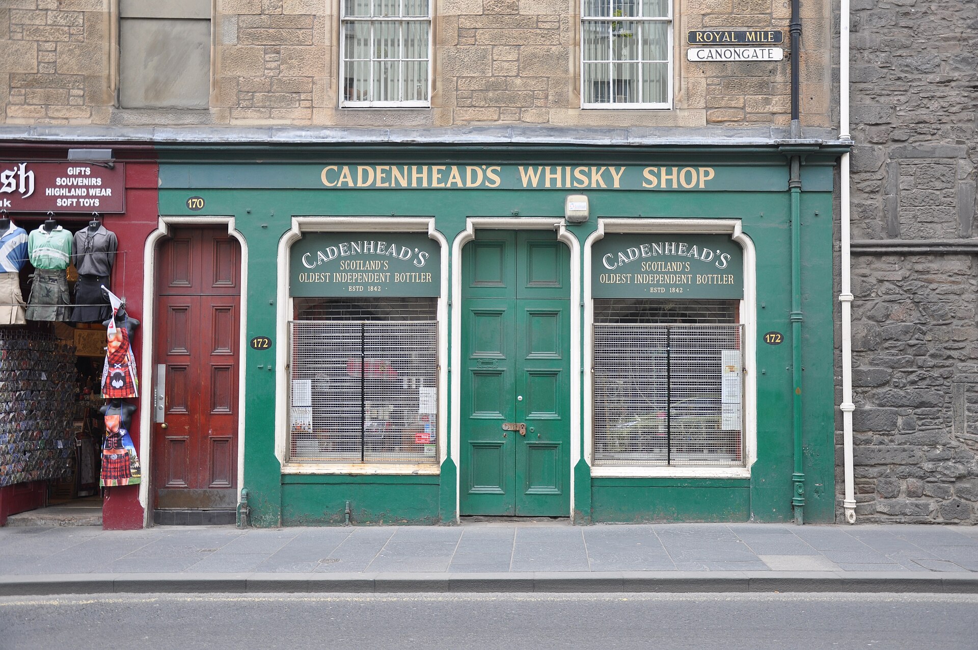 Cadenhead's green whisky shopfront on Edinburgh's Canongate has gold lettering, two display windows and a central wooden door.