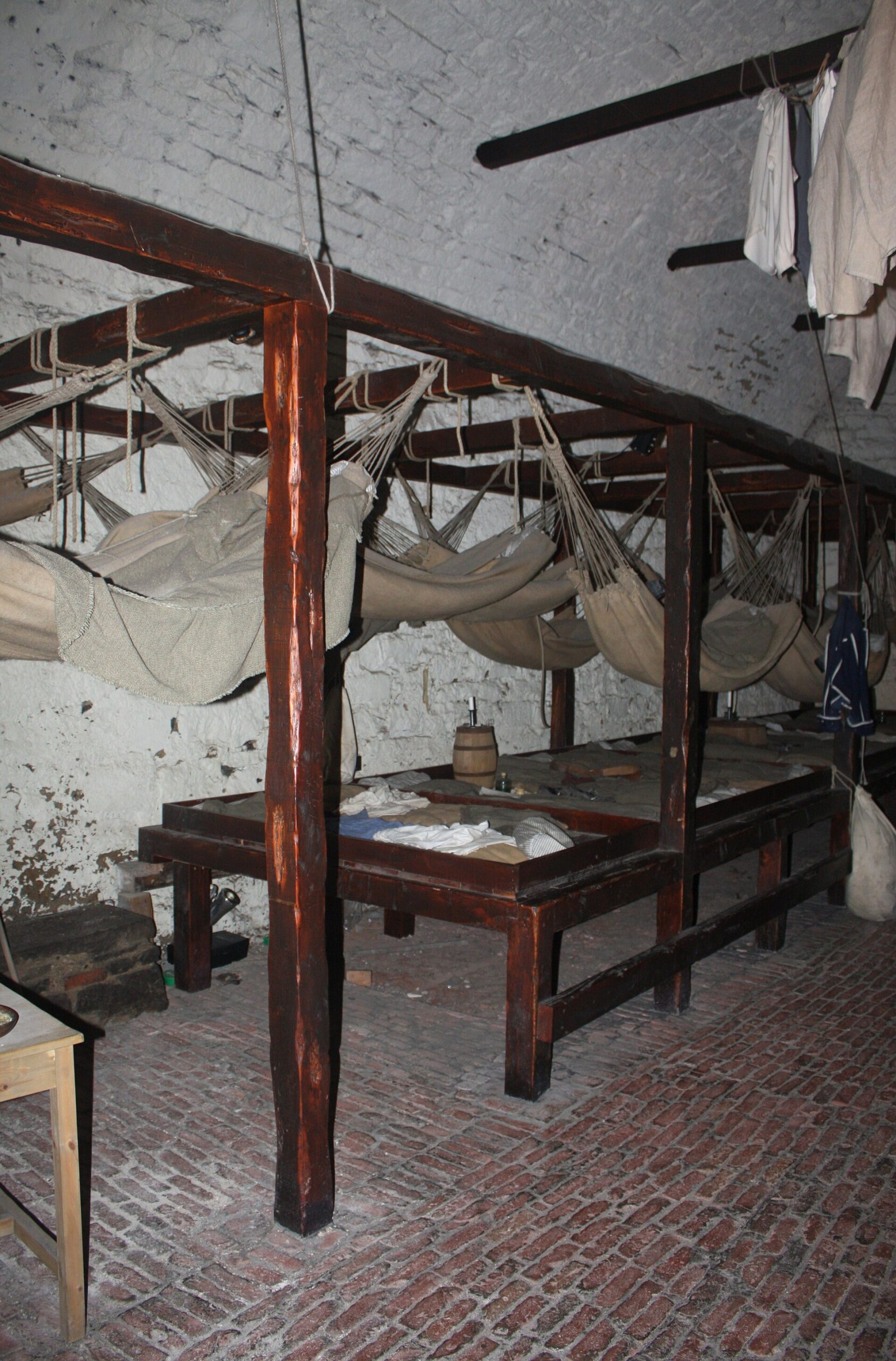 Canvas hammocks hang above wooden sleeping platforms beneath the whitewashed vaulted ceiling of Edinburgh Castle's prison exhibition.