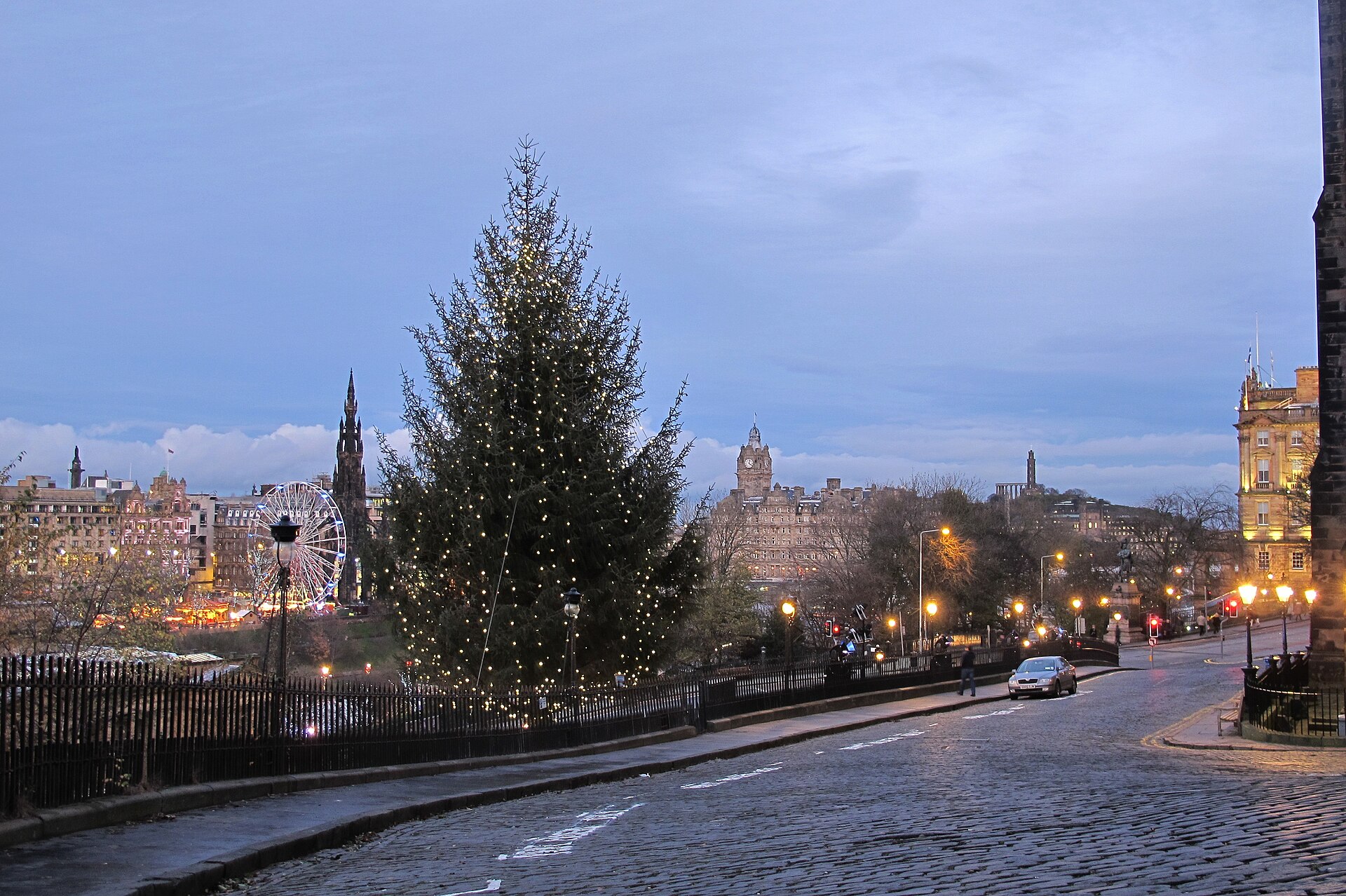 A Christmas tree covered in white lights stands on Edinburgh's Mound, overlooking the Big Wheel, Scott Monument and Balmoral clock tower.