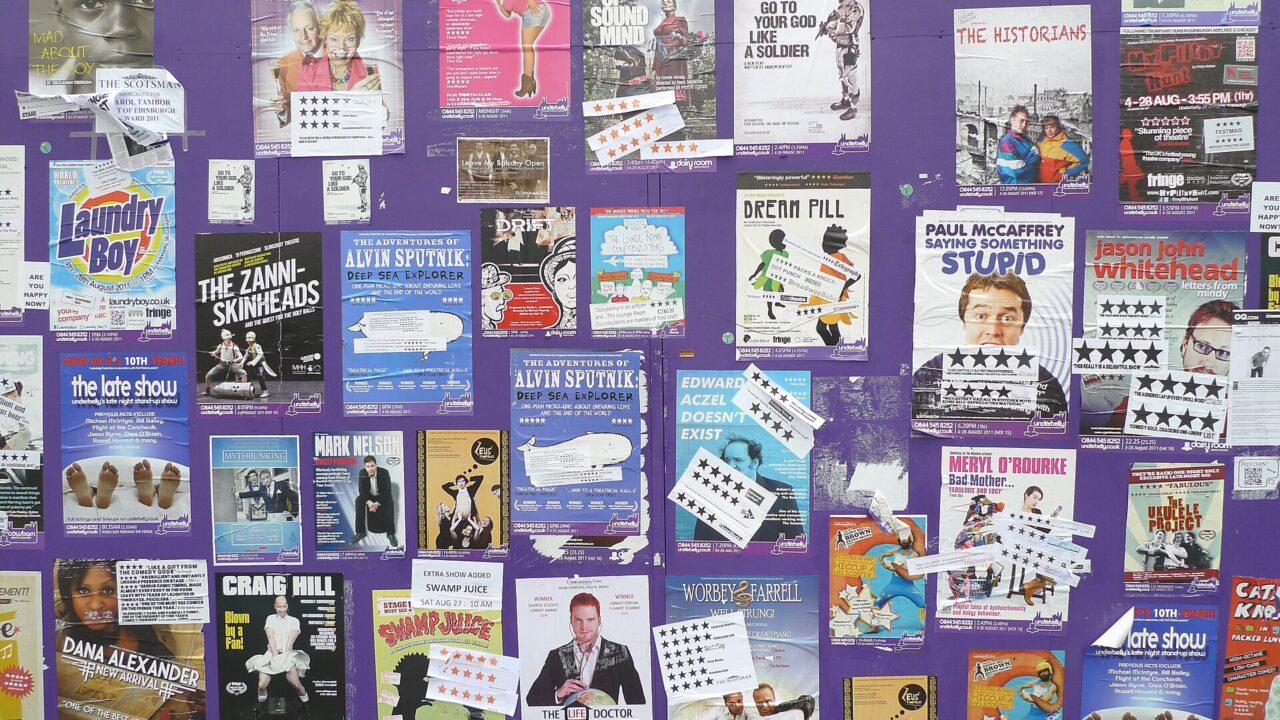 Colourful show flyers and star-rating stickers cover a purple display wall during Edinburgh's Festival Fringe in August 2011.