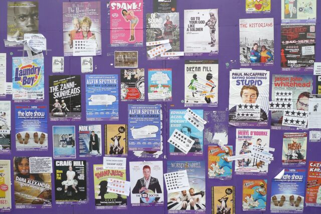 Colourful show flyers and star-rating stickers cover a purple display wall during Edinburgh's Festival Fringe in August 2011.