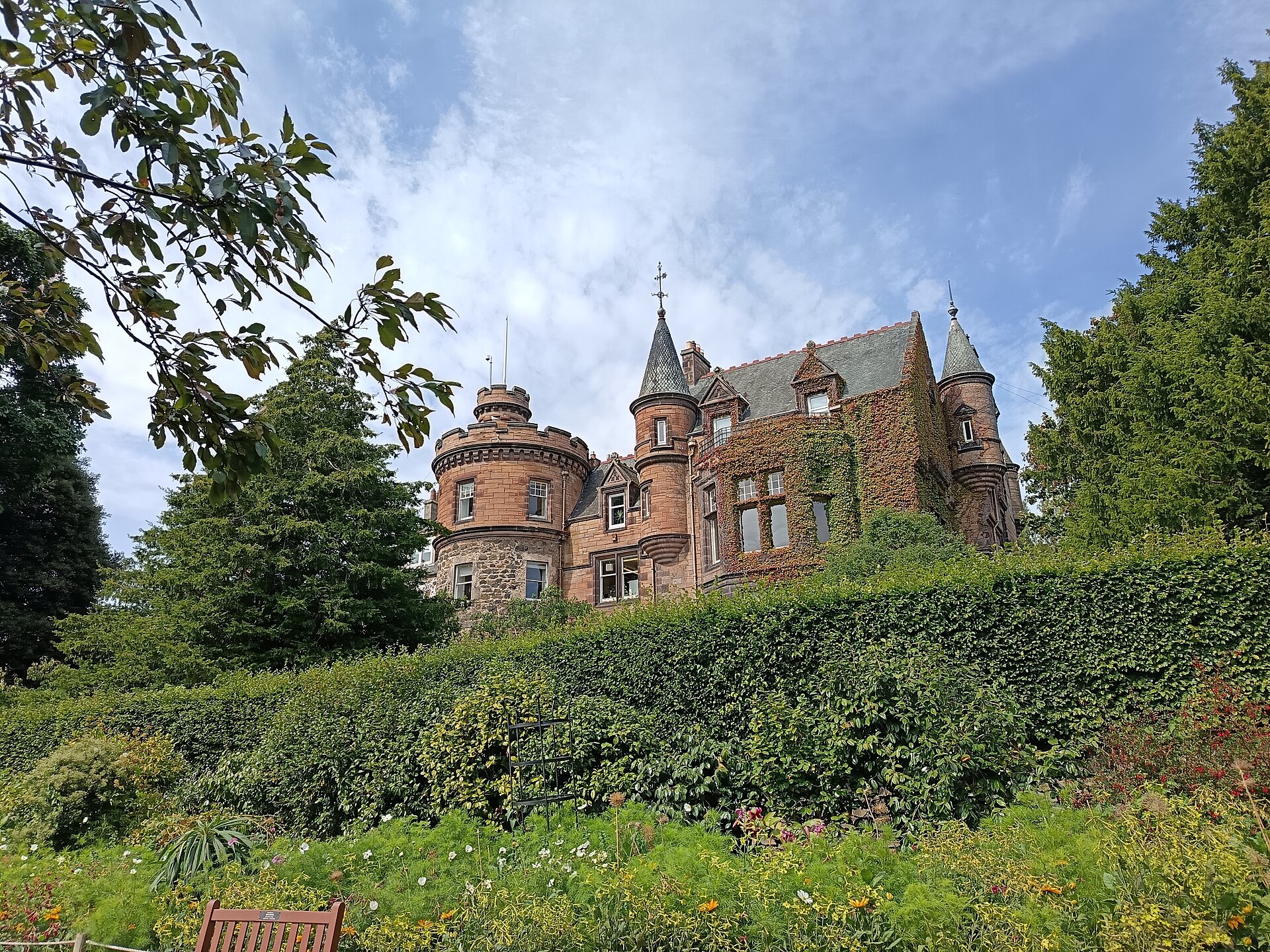 Corstorphine Hill House rises above sloping gardens at Edinburgh Zoo, with turrets, ivy and mature trees surrounding the stone building.