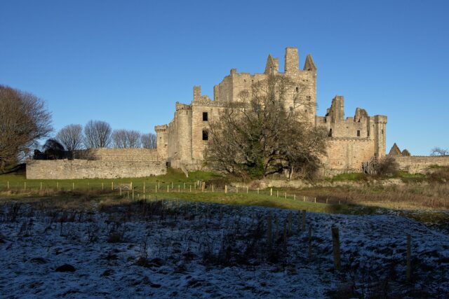 Craigmillar Castle in Edinburgh, with its ruined tower and curtain wall above a field dusted with snow.