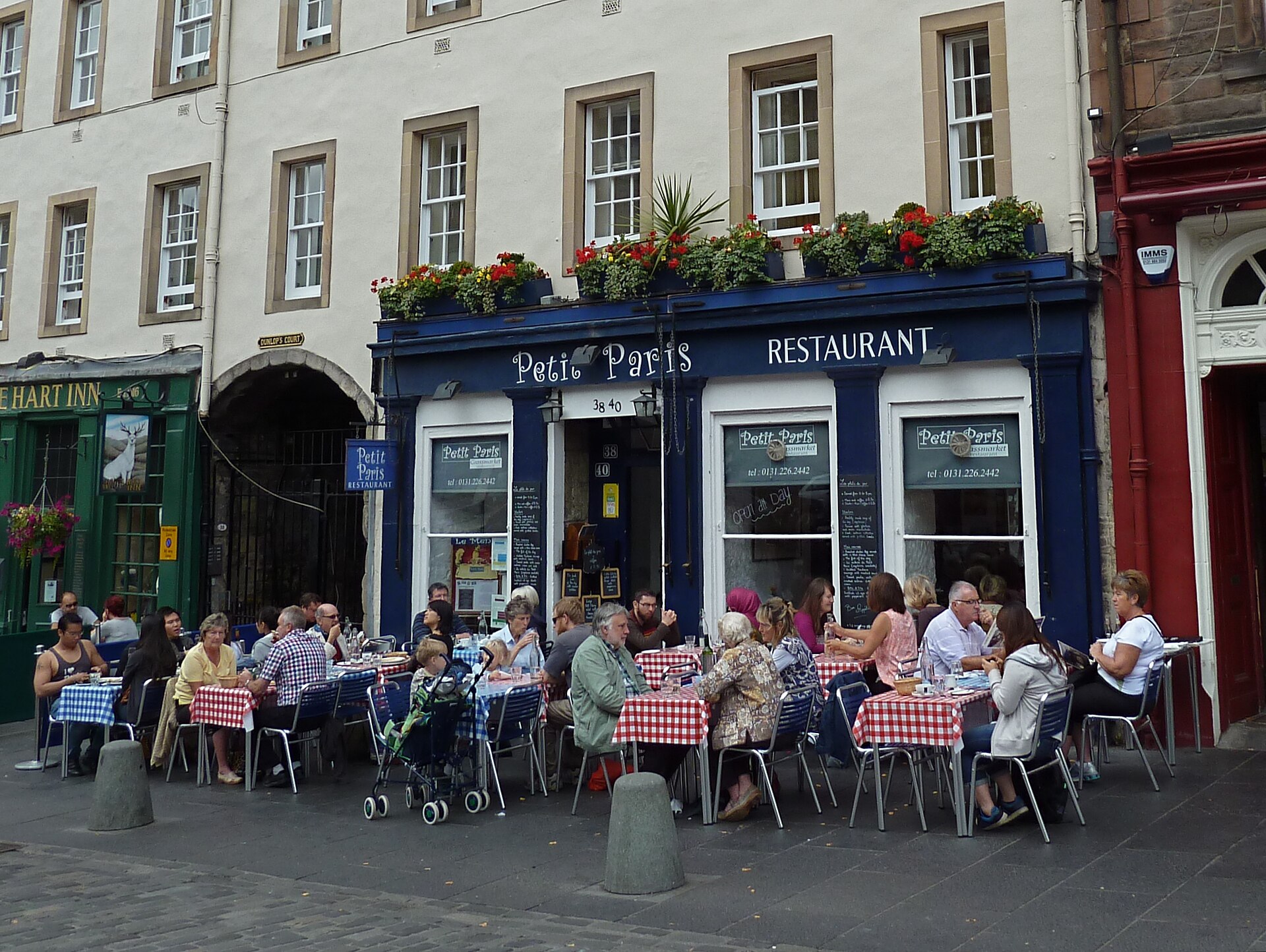 Diners sit at outdoor tables outside the blue-fronted Petit Paris restaurant on Edinburgh's Grassmarket.