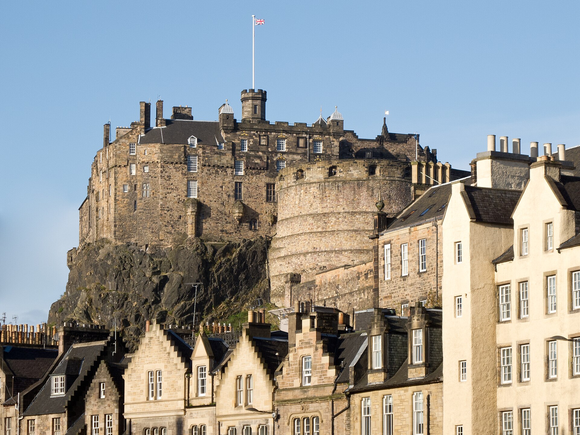 Edinburgh Castle's stone palace and curved defensive wall rise above the gabled rooftops of the Grassmarket.