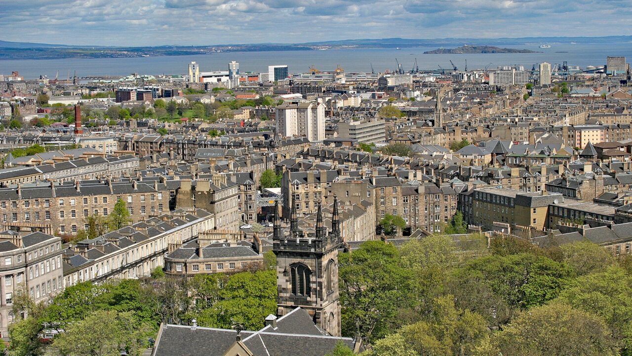 Edinburgh rooftops and the tower of Greenside Church stretch toward the Firth of Forth in this view from Calton Hill.
