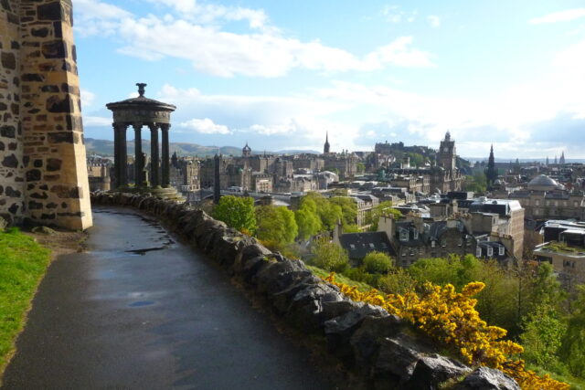 Edinburgh skyline from Calton Hill, with the Dugald Stewart Monument, Balmoral clock tower and castle above sunlit rooftops.