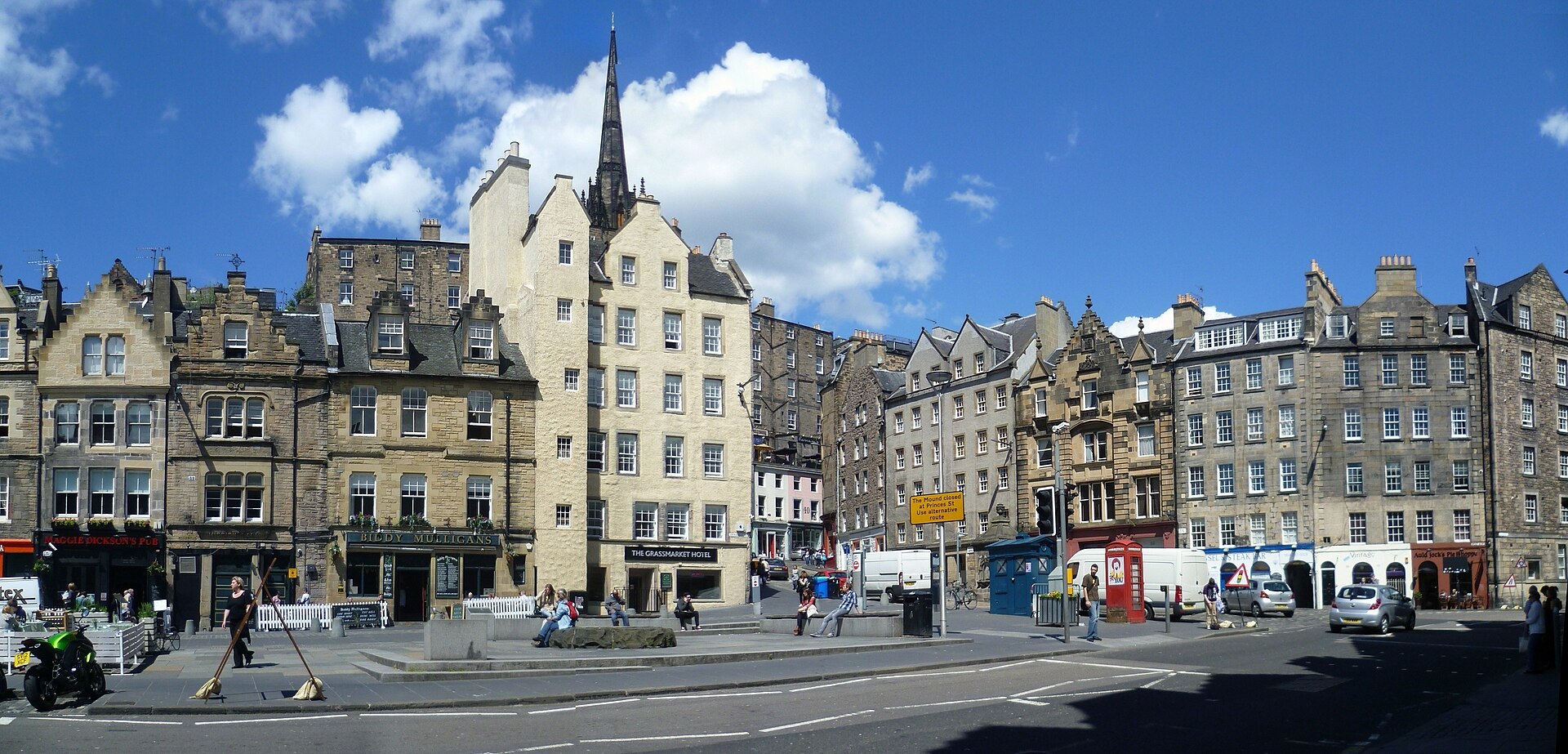 Gabled buildings, ground-floor businesses and a red telephone box face the eastern end of Edinburgh's Grassmarket square.