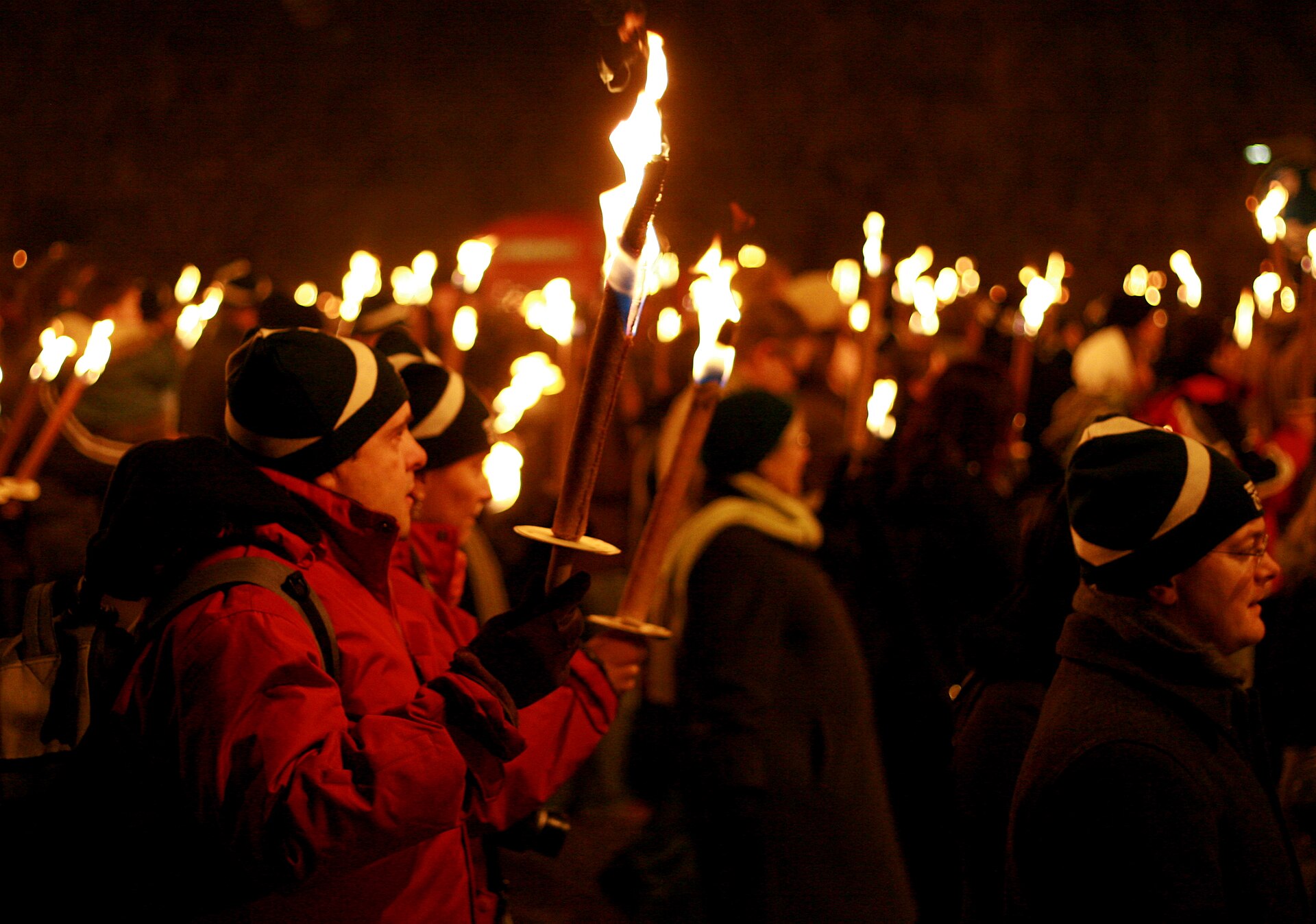 Participants carry flaming torches through the night during Edinburgh's Hogmanay torchlight procession on Calton Hill.