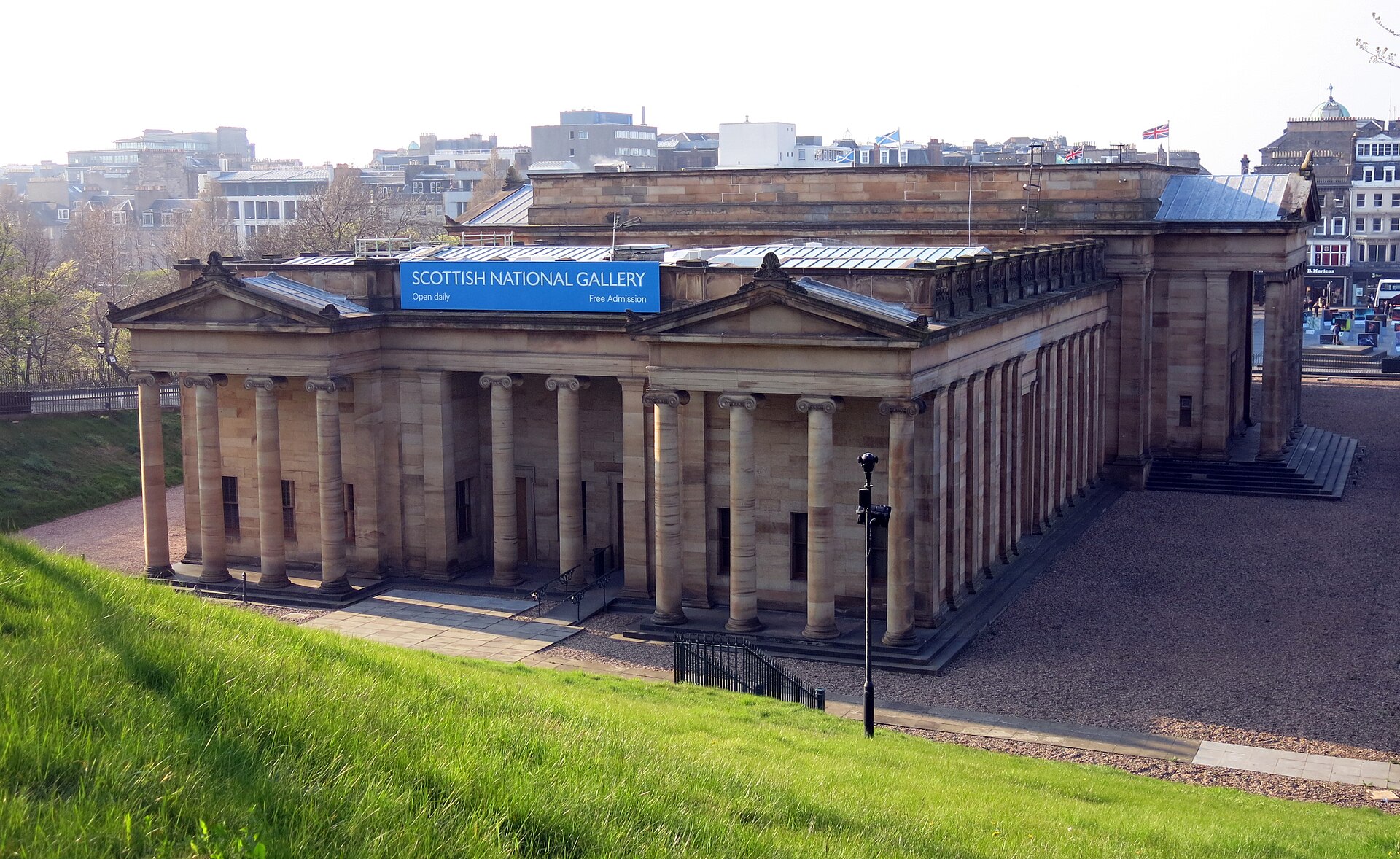 The Scottish National Gallery in Edinburgh, with sandstone columns, twin pediments and a grassy slope in the foreground.