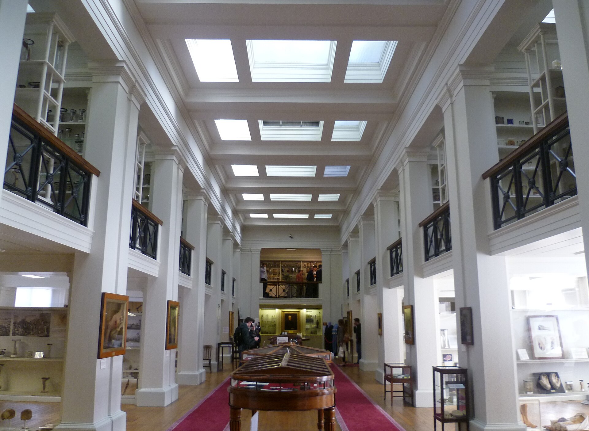 Skylights illuminate specimen cabinets, white columns and wooden display cases inside Edinburgh’s Surgeons’ Hall Museum.