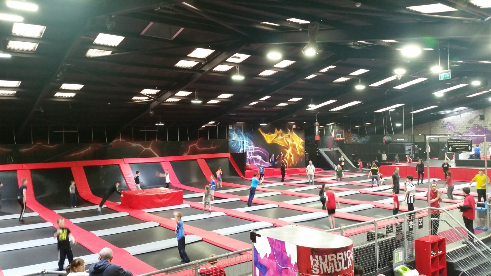 Visitors bounce across interconnected black trampolines with red padded borders inside Ryze Edinburgh at Newtongrange.