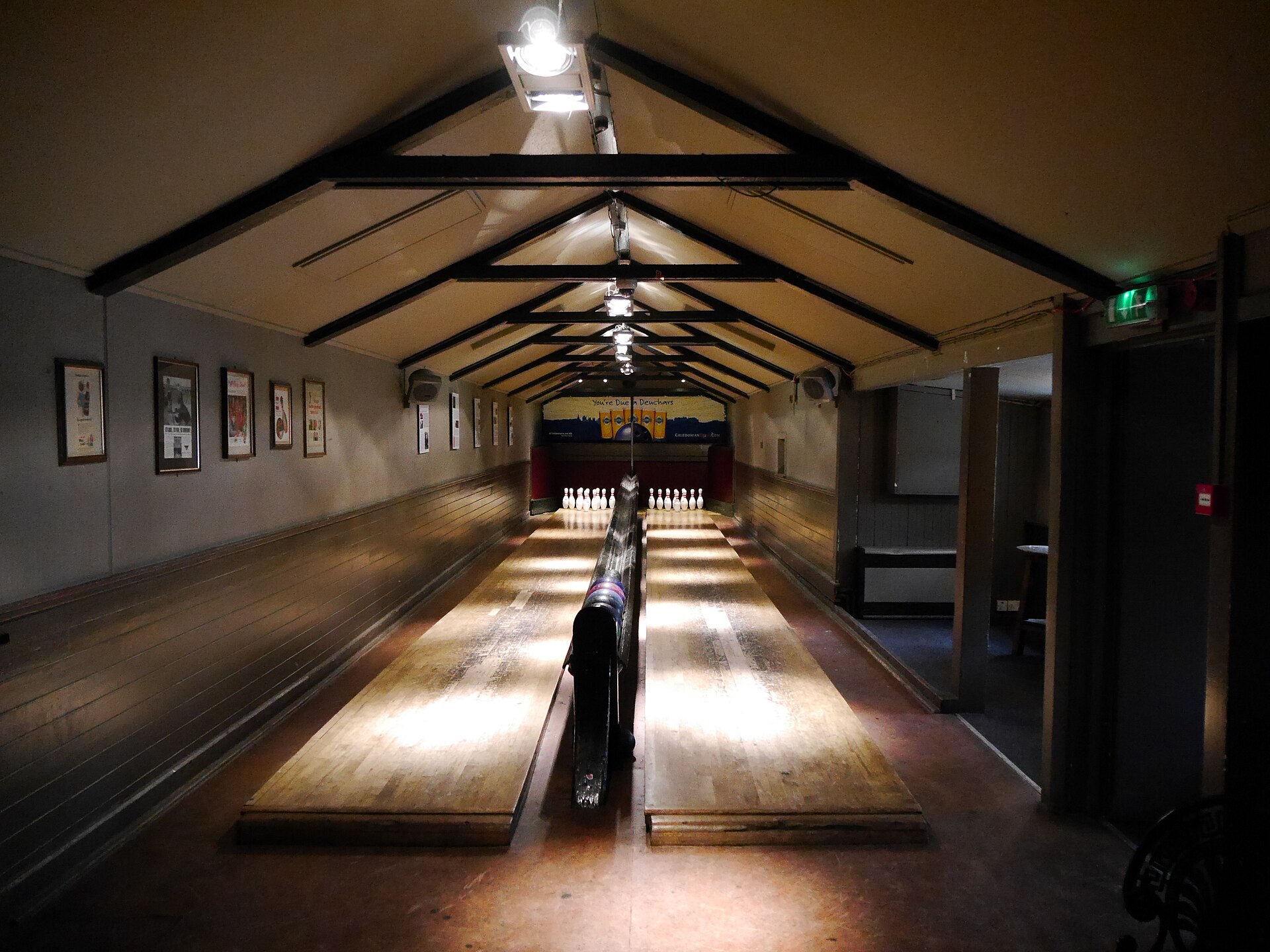 Wooden skittle lanes and rows of pins beneath dark roof trusses inside the Sheep Heid Inn, Edinburgh.